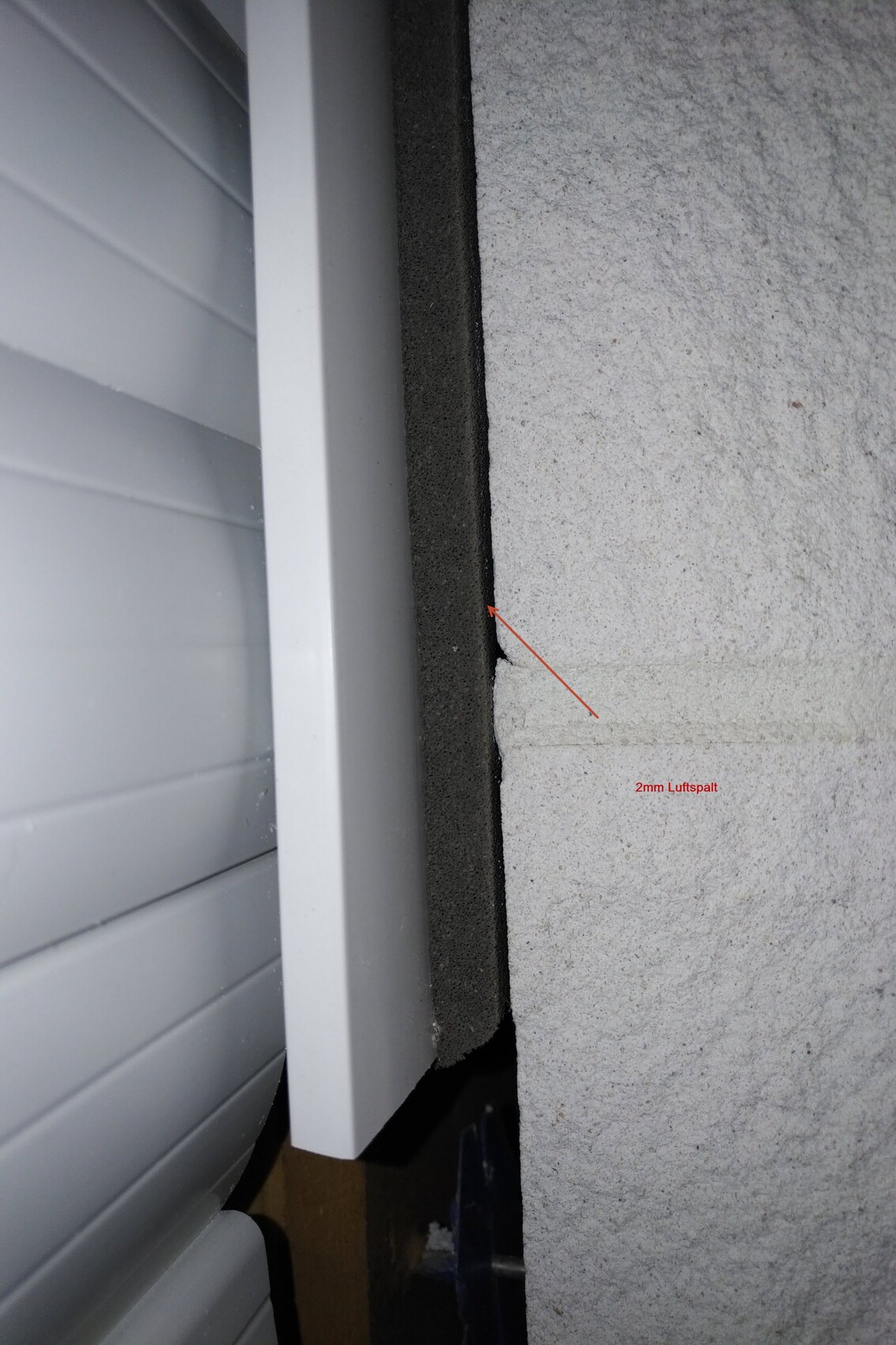 Nahaufnahme eines Fensterrahmens mit Dämmung und sichtbarem 2mm Luftspalt an der Gebäudewand