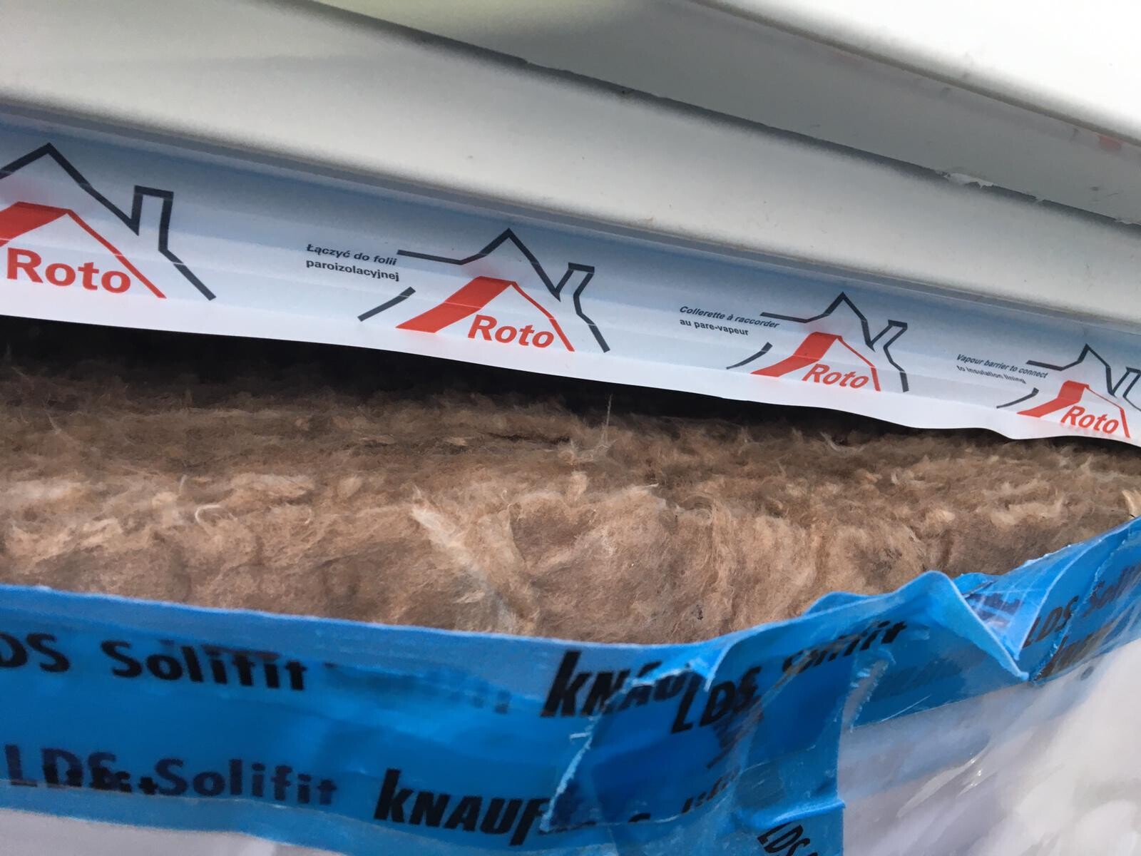 Nahaufnahme von Dämmstoff zwischen Bauteilen mit blauem Schutzband