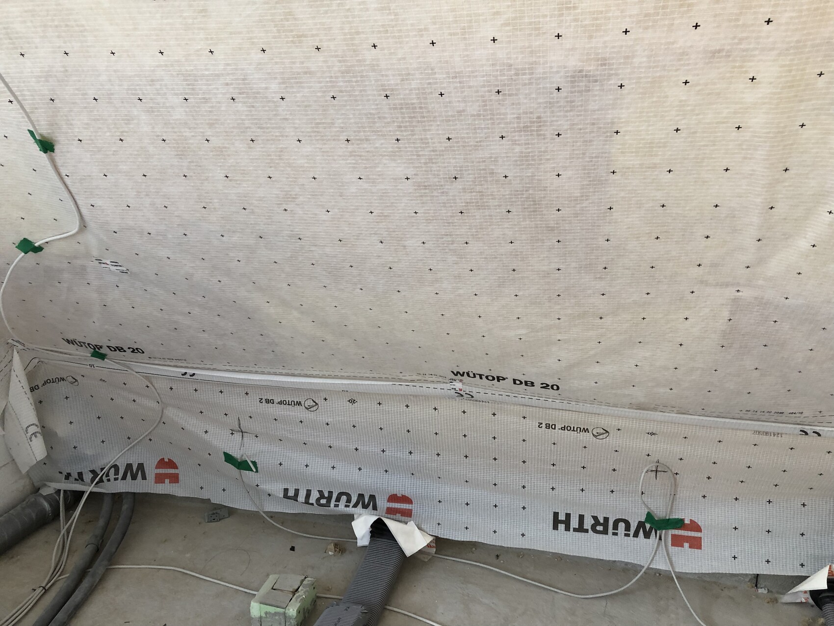 Baustellenwand mit Dämmstoffplatte WÜTOP DB 20, Kabeln und Rohren am Boden.