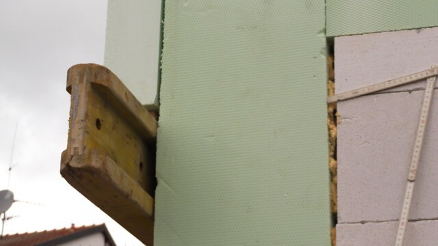 Außenwand mit grüner Dämmplatte und Holzhalterung bei Bauarbeiten