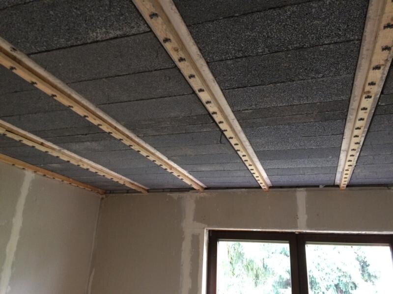 Unfertige Decke mit sichtbaren Holzbalken, Dämmplatten und Fenster im Raum