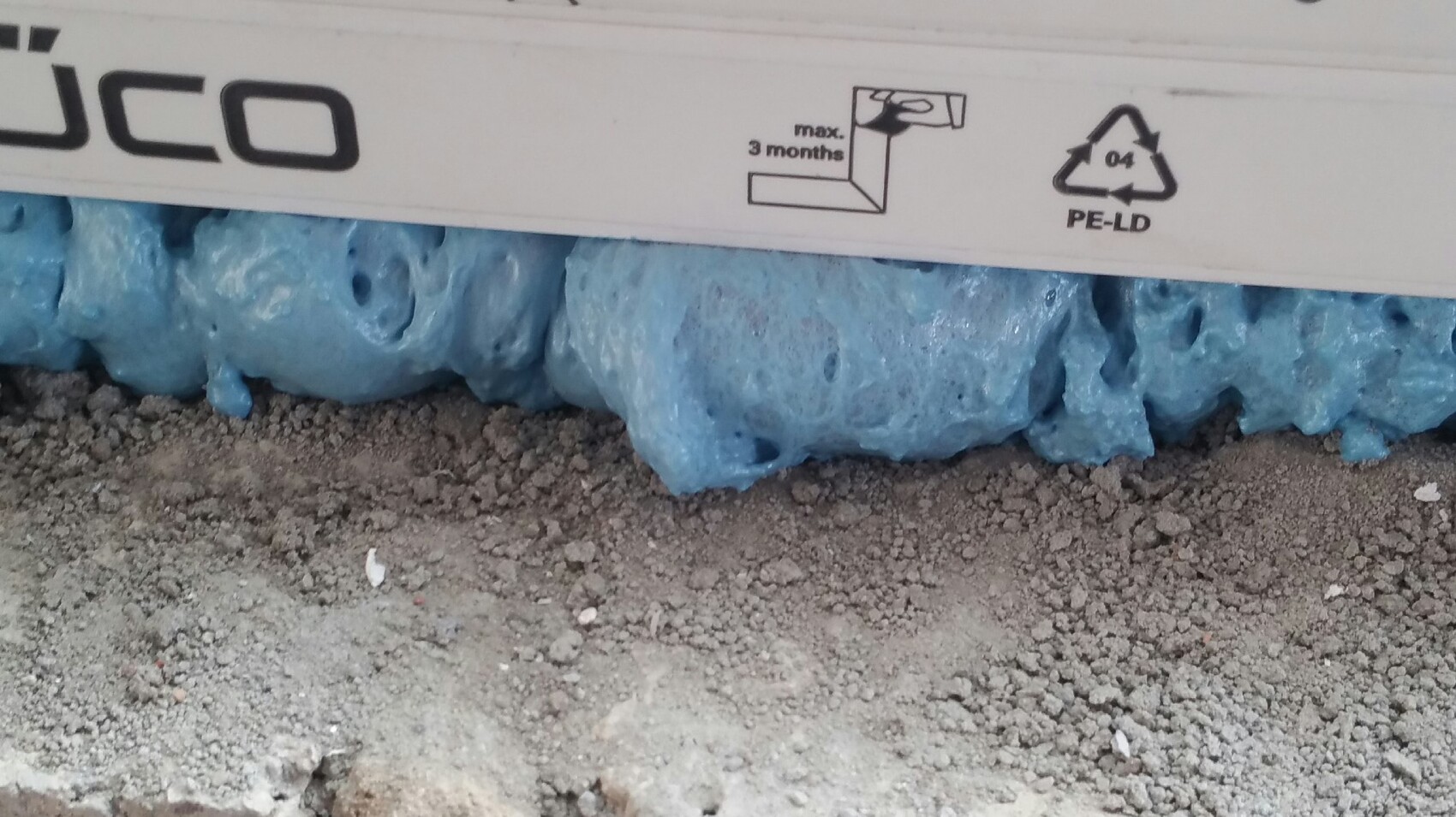 Blaue Dämmung aus Schaumstoff am Fundament neben Kiesboden bei Bauarbeiten