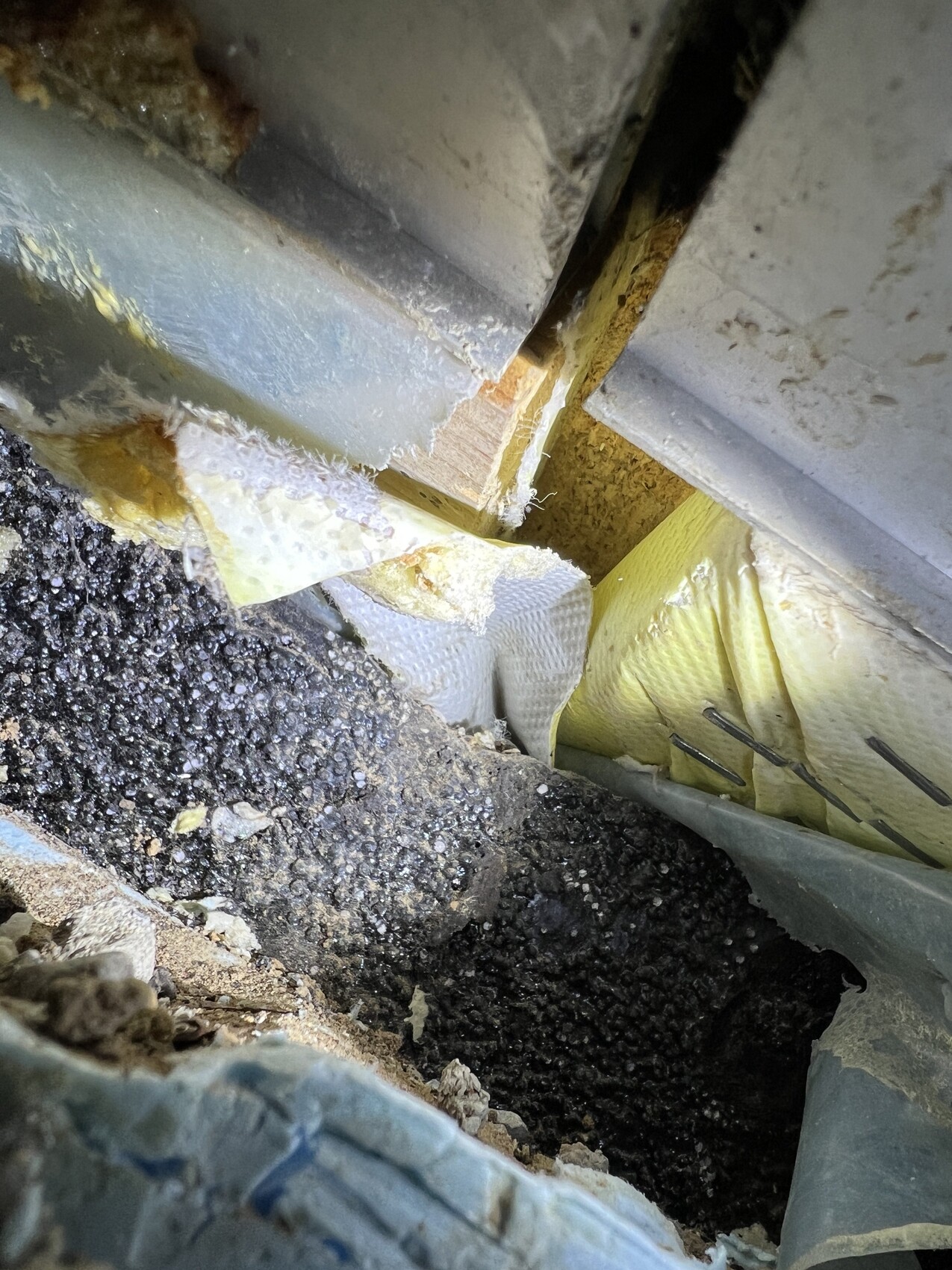 Baustelle mit gelber Dämmung in Wandzone, Erdreich und Baumaterial sichtbar.