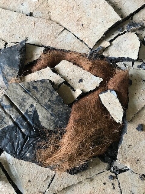 Aufgerissene Wand mit braunem Dämmmaterial aus Fasern zwischen zersplittertem Putz.