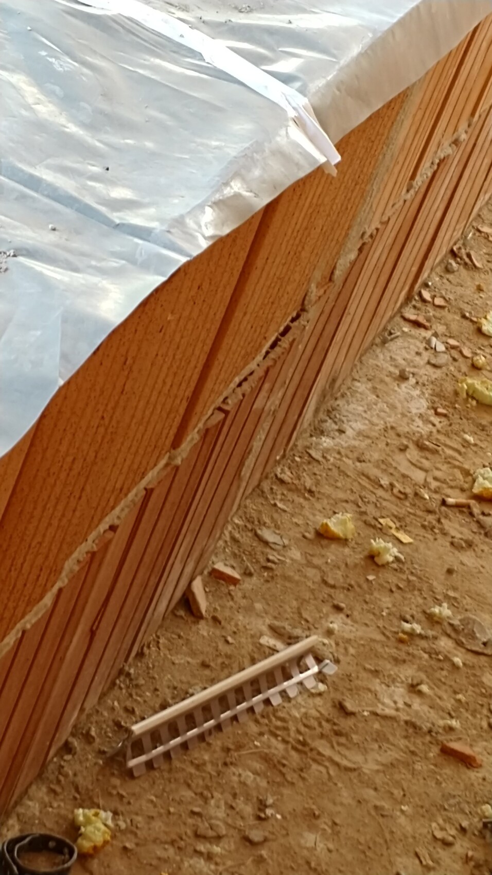 Baustelle mit Holzverkleidung, Baufolie und losem Dämmmaterial am Boden
