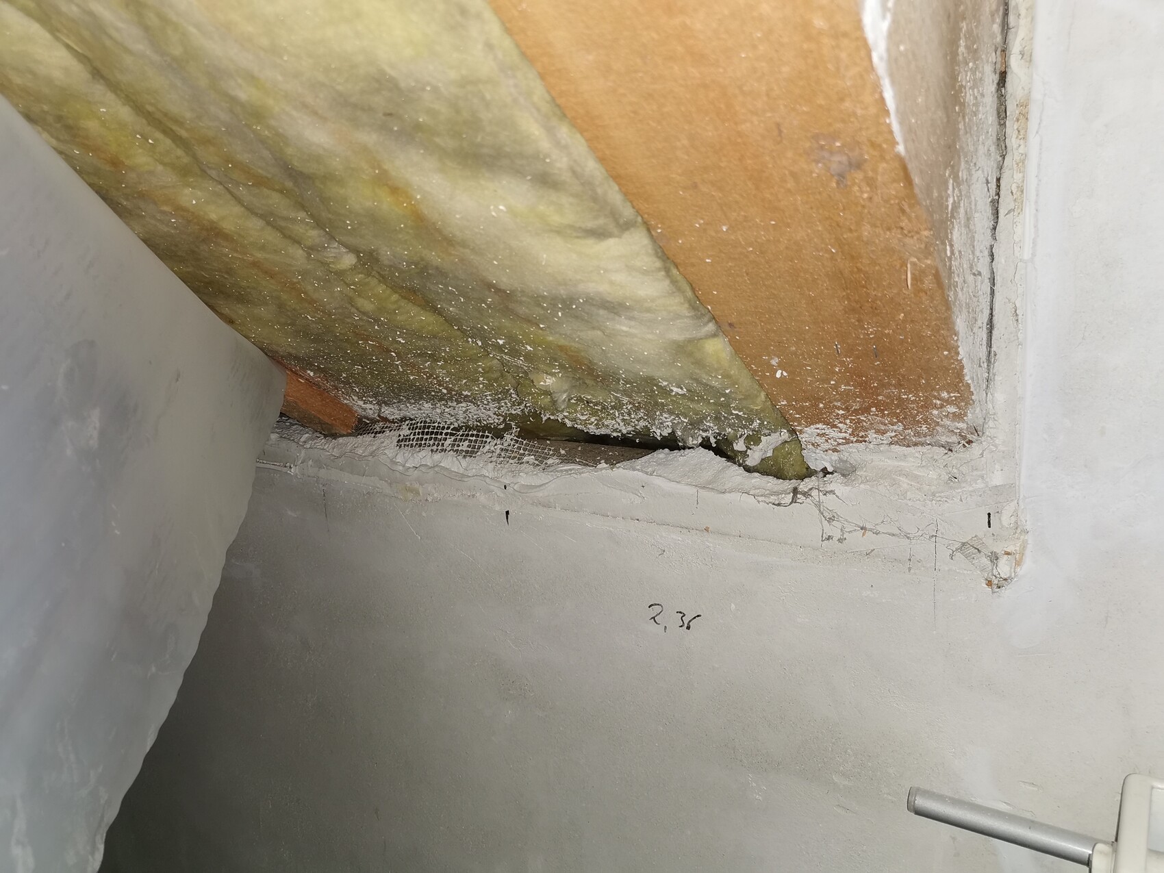 Offene Wand/Deckenstelle mit Dämmung, Netzgewebe und Putzresten.