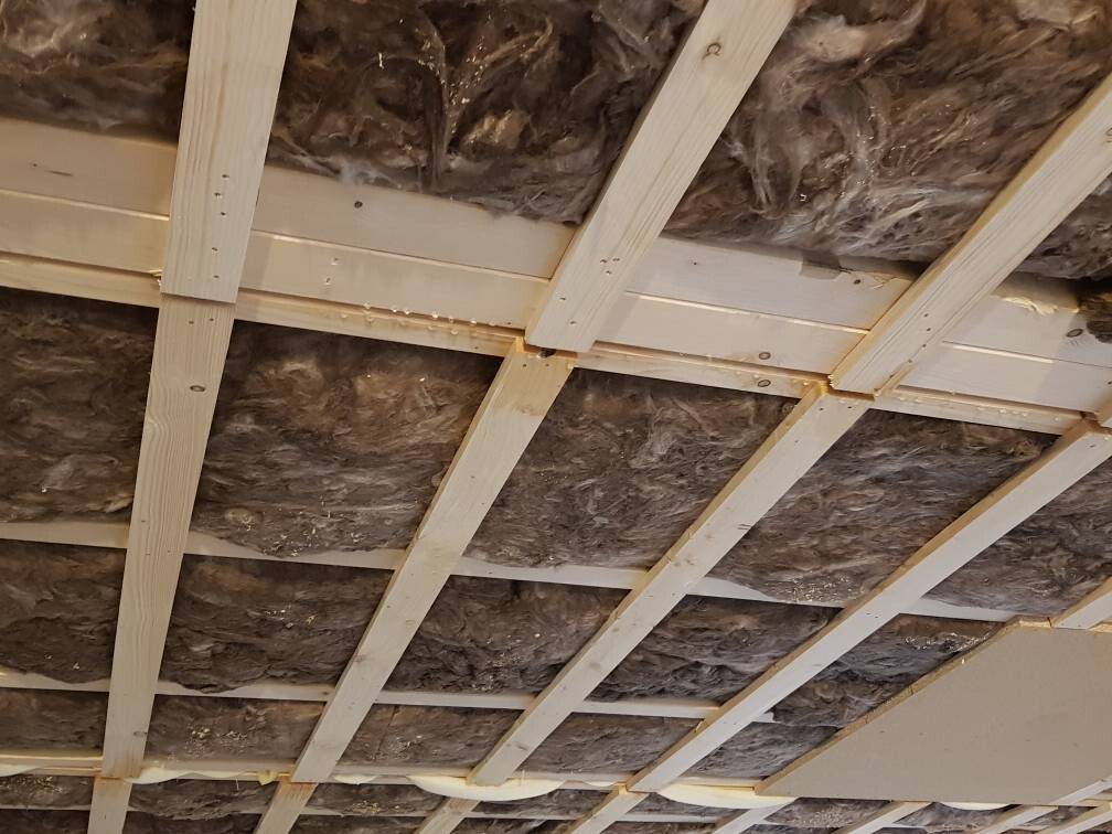 Rohbau-Decke mit sichtbarer Holzbalkenstruktur und Dämmung zwischen den Balken