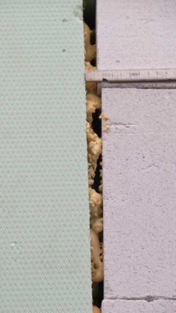 Nahaufnahme von Dämmmaterial zwischen grüner Isolationsplatte und Betonbausteinen