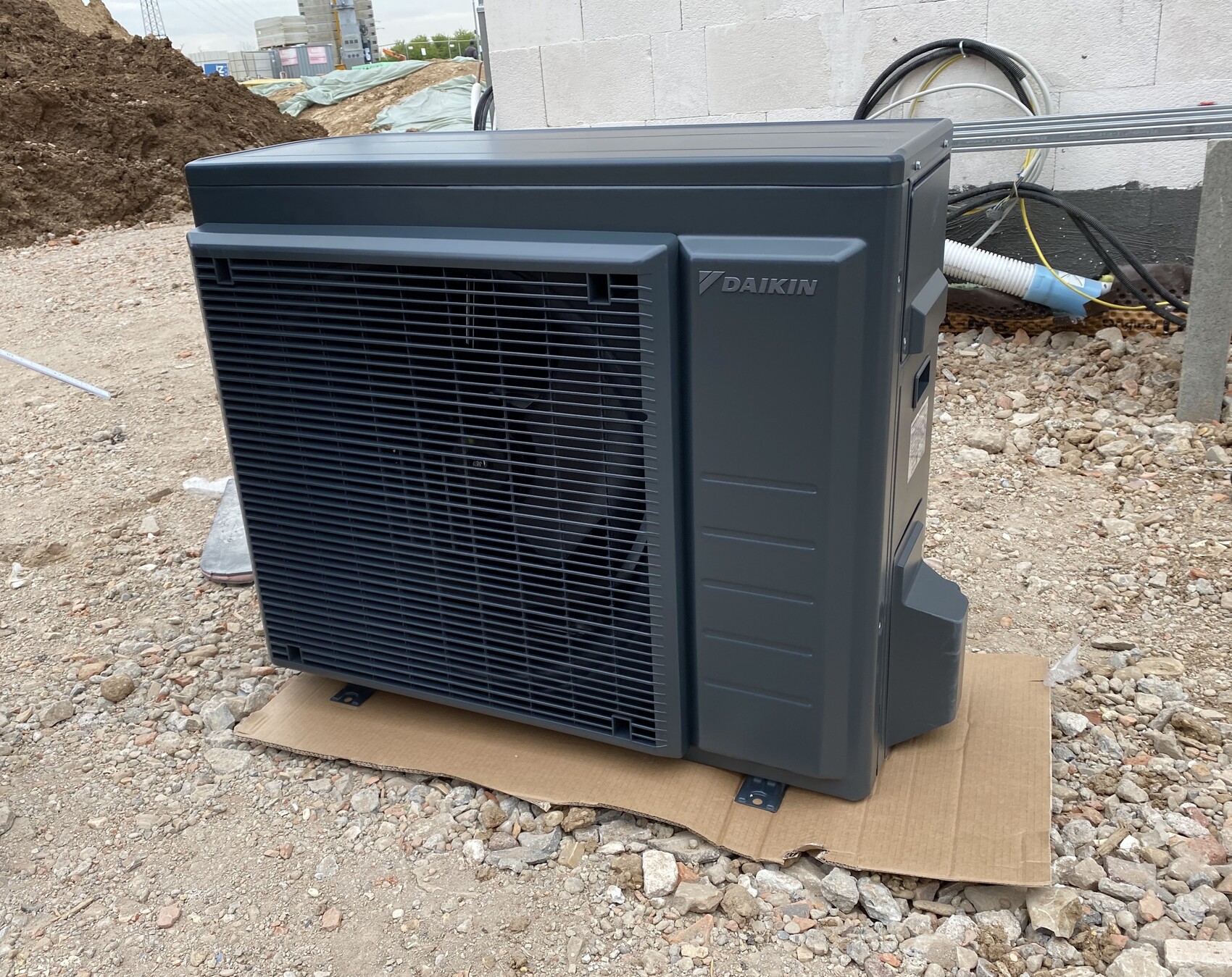 Daikin-Klimagerät im Freien auf einer Baustelle, steht auf Karton auf Kies.