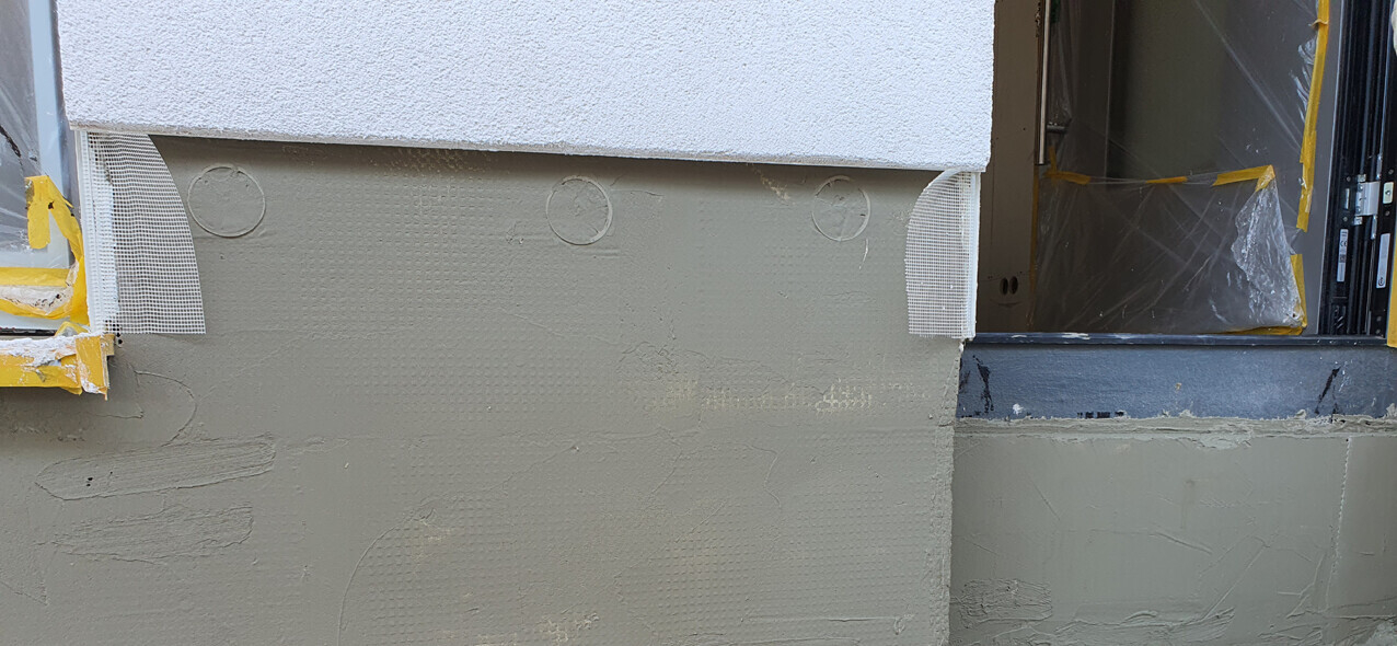 Außenwand mit Dämmung, Putzschicht und Schutzfolie am Türrahmen