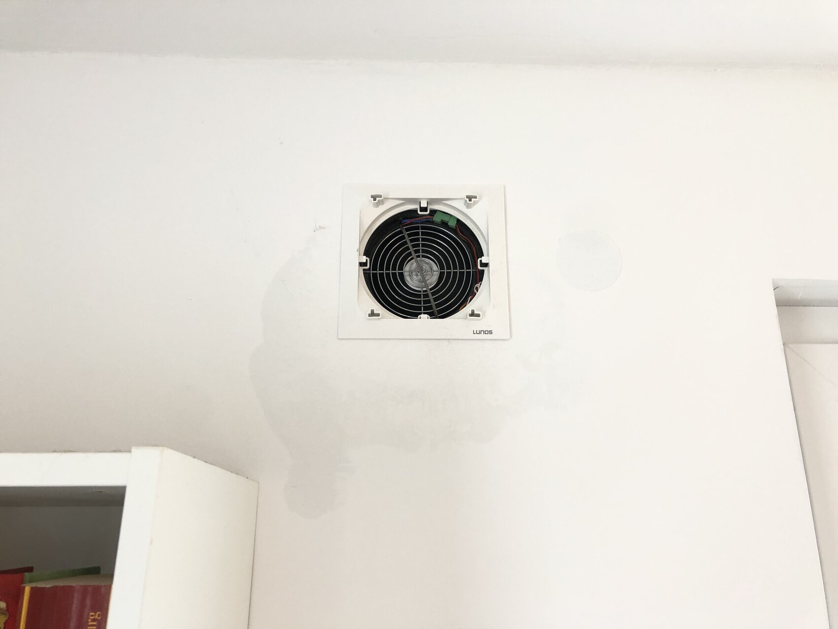 Weißer Raum mit Deckenauslass-Lüftungsventilator im quadratischen Rahmen an der Wand