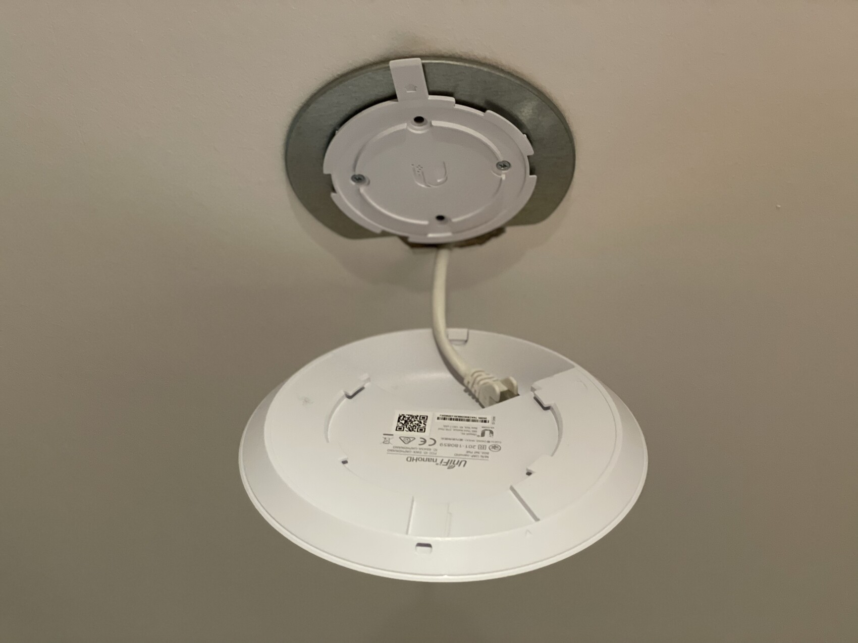 Weiße runde Deckenleuchte mit Montagesystem und Kabel an der Decke.