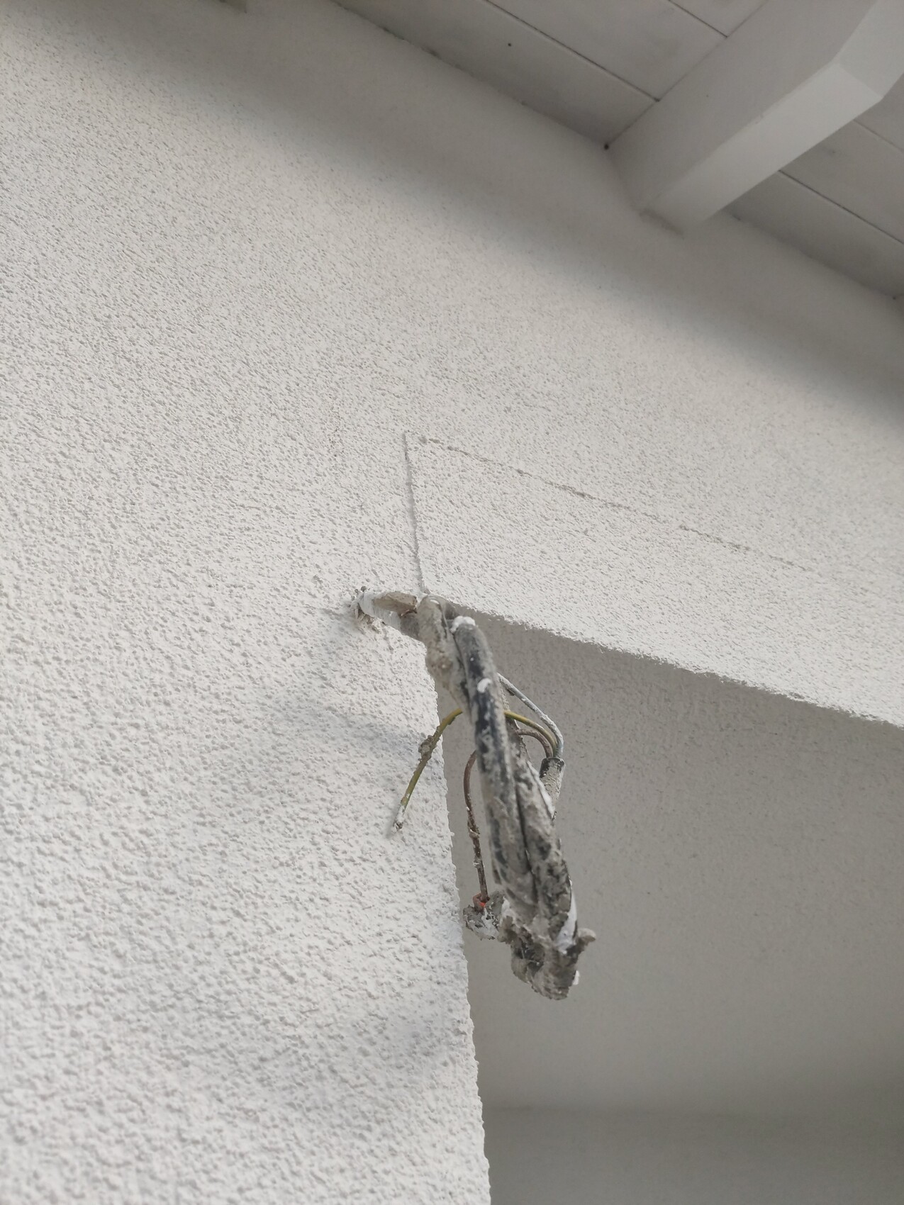 Außenwand mit freiliegendem Kabelbündel und losem Draht.