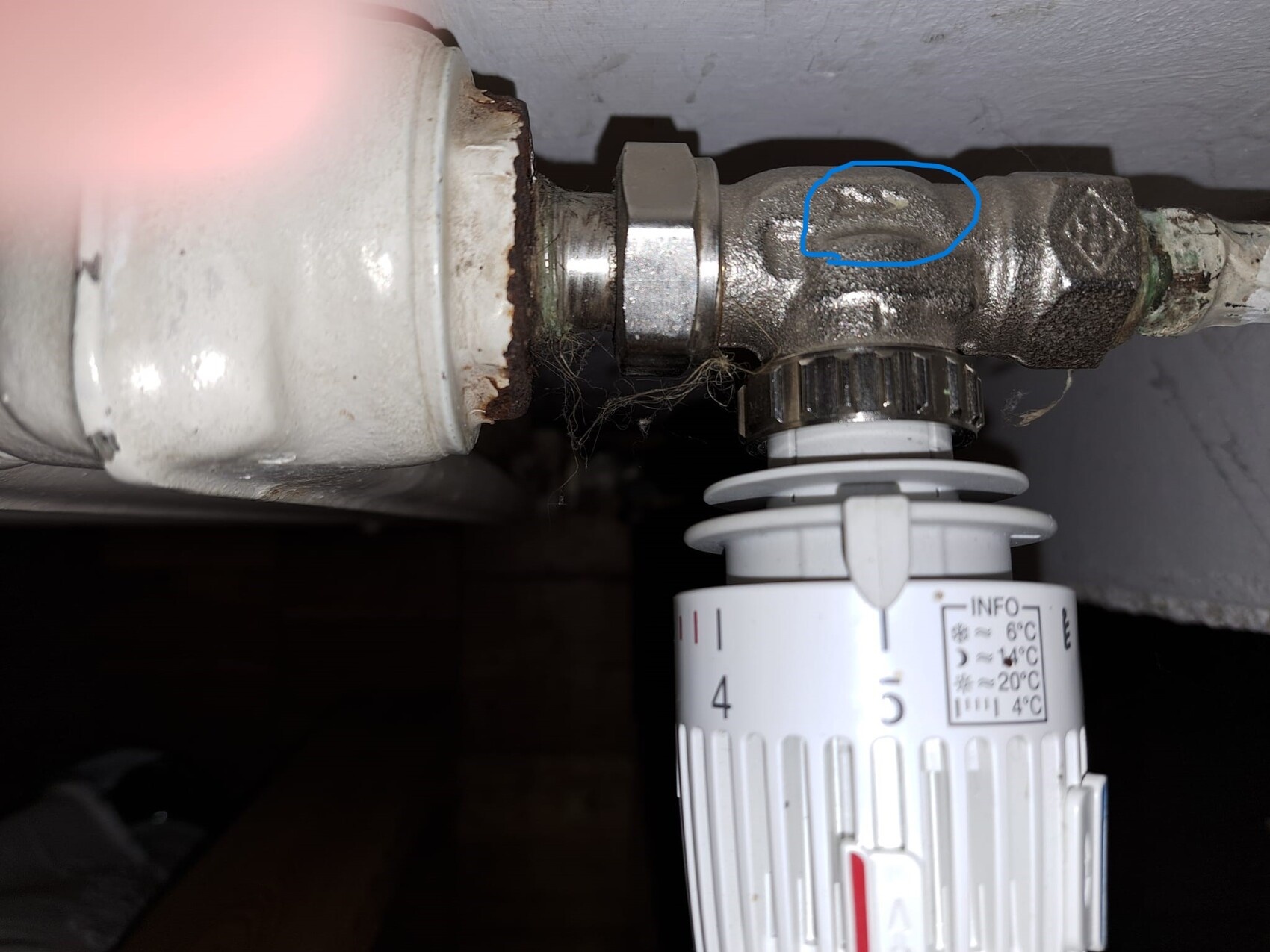 Unter dem Waschbecken: Metallventil mit Thermostat; blau markierte Beschädigung am Ventil.