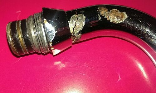 Beschädigte Rohrleitung mit Korrosion in der Haustechnik vor rotem Hintergrund.