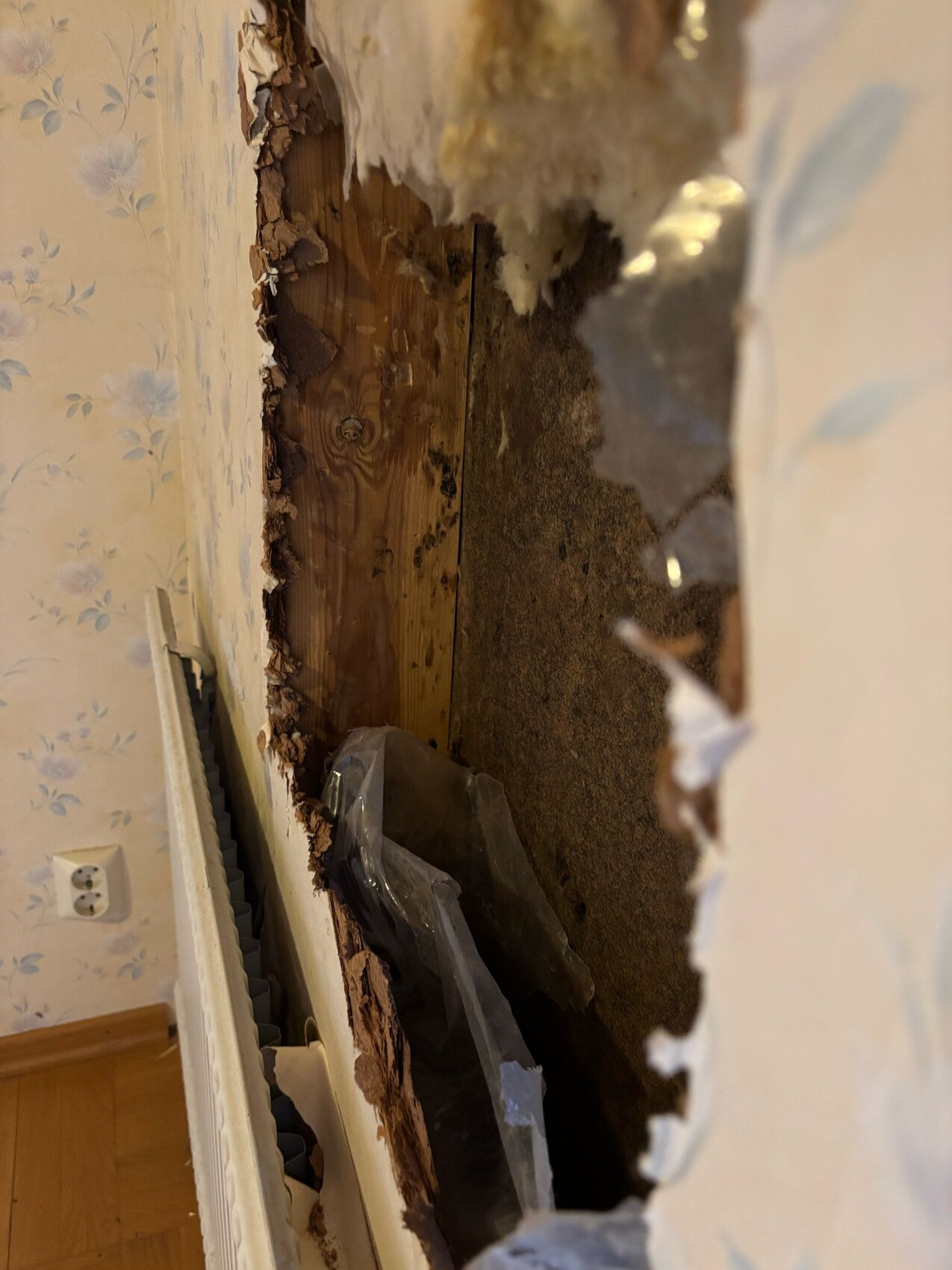 Wanddurchbruch zeigt freiliegtes Holzständerwerk, Putzreste und Dämmmaterial im Hohlraum.