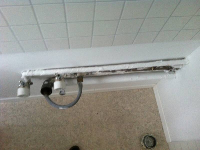 Badezimmer-Türrahmen mit defekter Rohrleitung und Wandbeschädigung