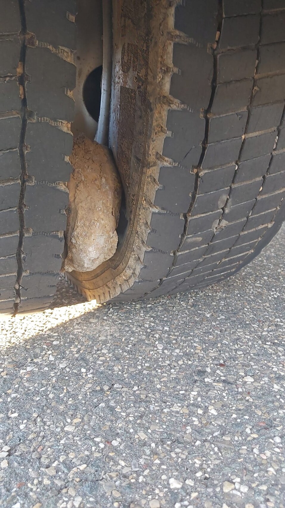 Nahaufnahme eines Autoreifens mit deutlicher Beule an der Seitenwand und Schlamm am Boden.