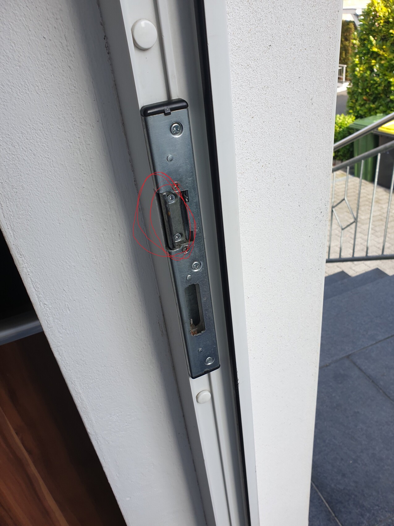 Türrahmen mit defektem Türbeschlag und sichtbaren Schrauben am Türschlossbereich