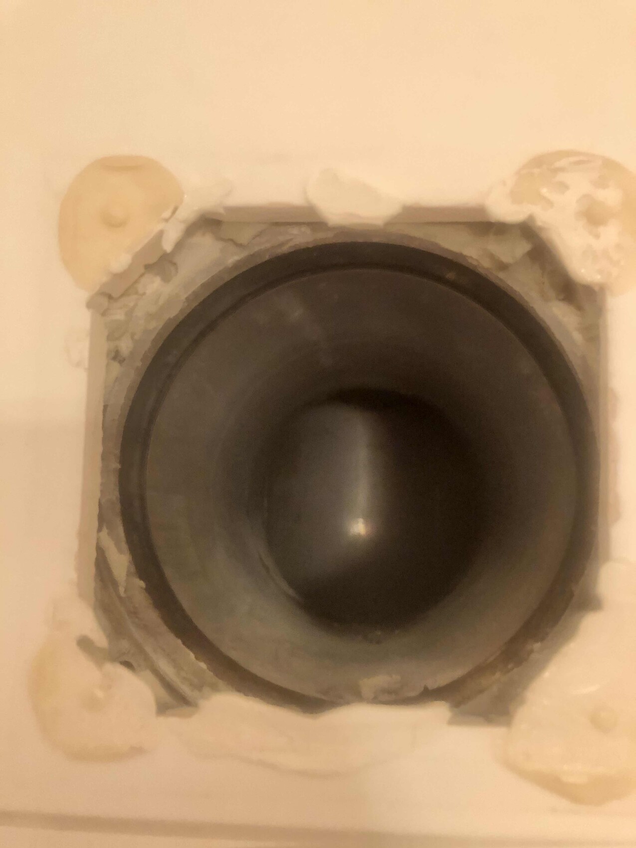 Runde Rohröffnung in beschädigter Wand mit Metallrohr und Putzresten ringsum.