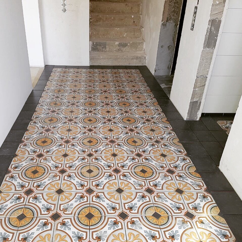 Flur mit dekorativen gemusterten Bodenfliesen und Treppe im Hintergrund