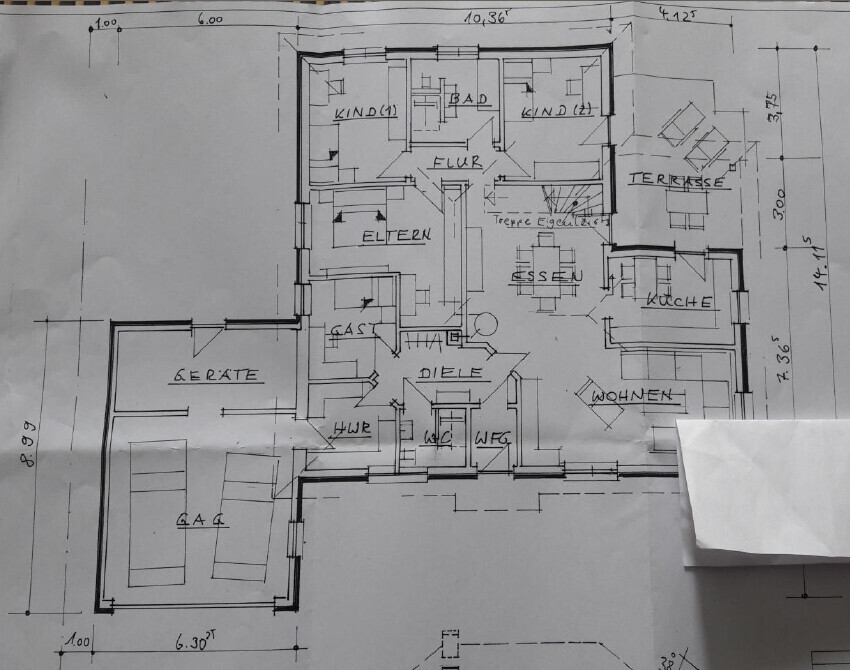 Grundriss eines Einfamilienhauses mit Wohnzimmer, Küche, Esszimmer, Terrasse und Garage.