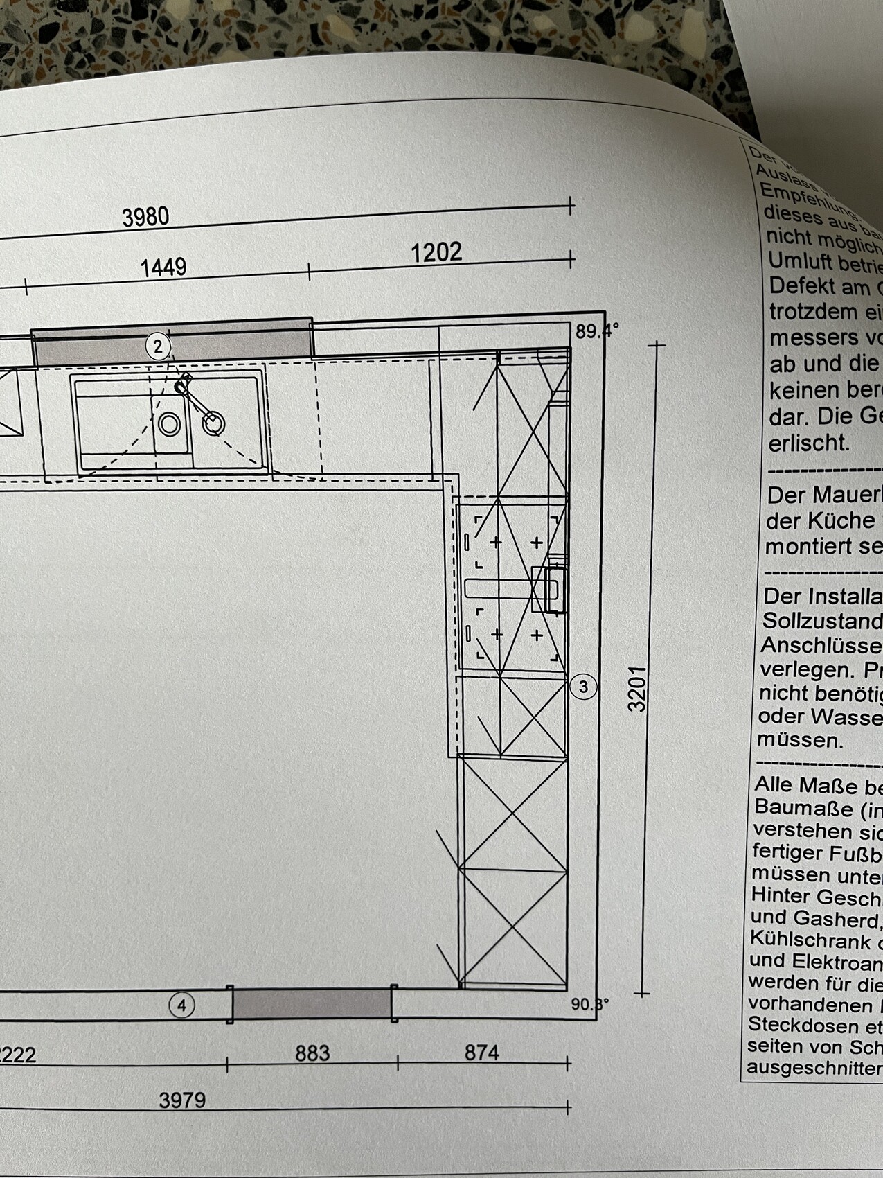 Grundriss eines Küchenplans mit Spüle, Arbeitsflächen im Eckbereich und Maßlinien.