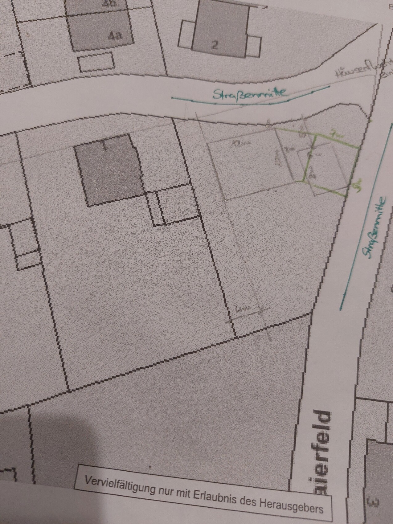 Lageplan eines Baugebiets mit Grundstücksparzellen, Straße in Mittellage und grün markierten Anmerkungen.