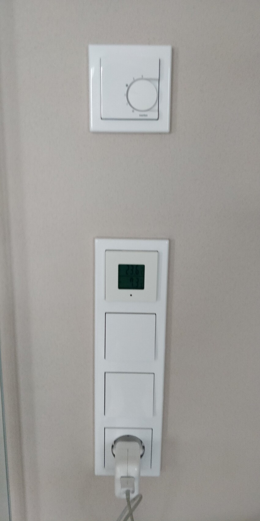 Weißes Wandgerät mit Digitaldisplay und mehreren Lichtschaltern an der Wand