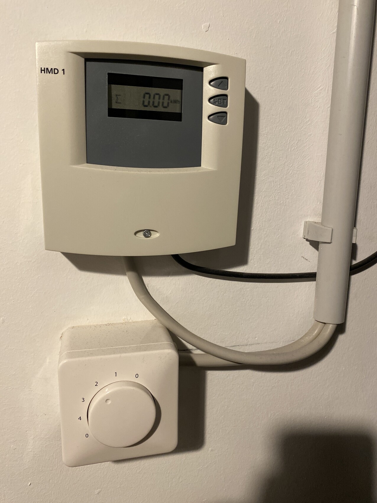HMD 1 Thermostat mit Digitaldisplay und daneben rundem Drehknopf, durch Kabel verbunden.