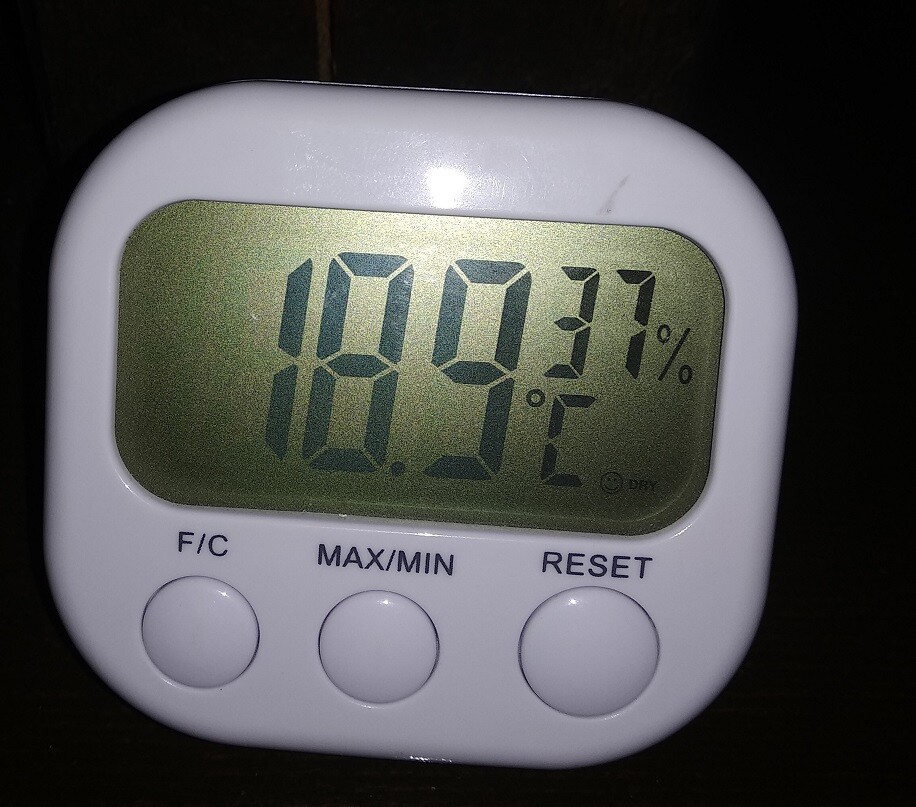 Weißes digitales Hygrometer mit Anzeige der Raumfeuchtigkeit ca. 89% und drei Knöpfen.