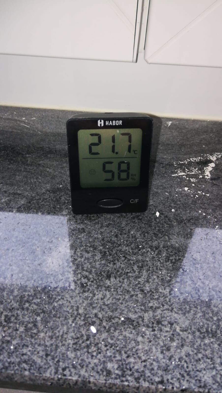 Digitales Thermo-Hygrometer zeigt 21,7°C und 58% Luftfeuchte auf dunkler Granitplatte.
