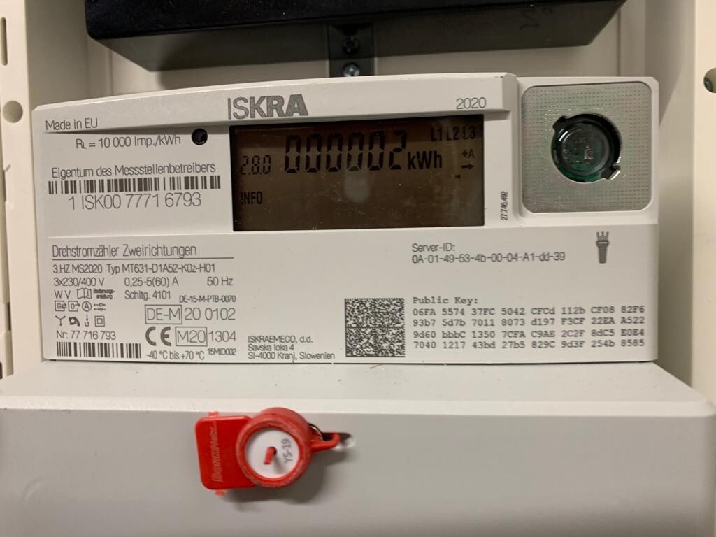 ISKRA-Stromzähler mit digitaler Anzeige und rotem Sicherheits-Siegel.