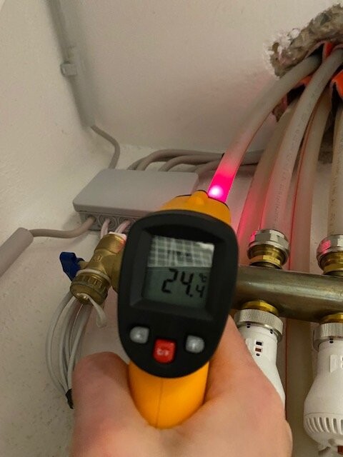 Infrarot-Thermometer misst Rohrtemperatur; Anzeige 24,4 °C; roter Laser darauf gerichtet