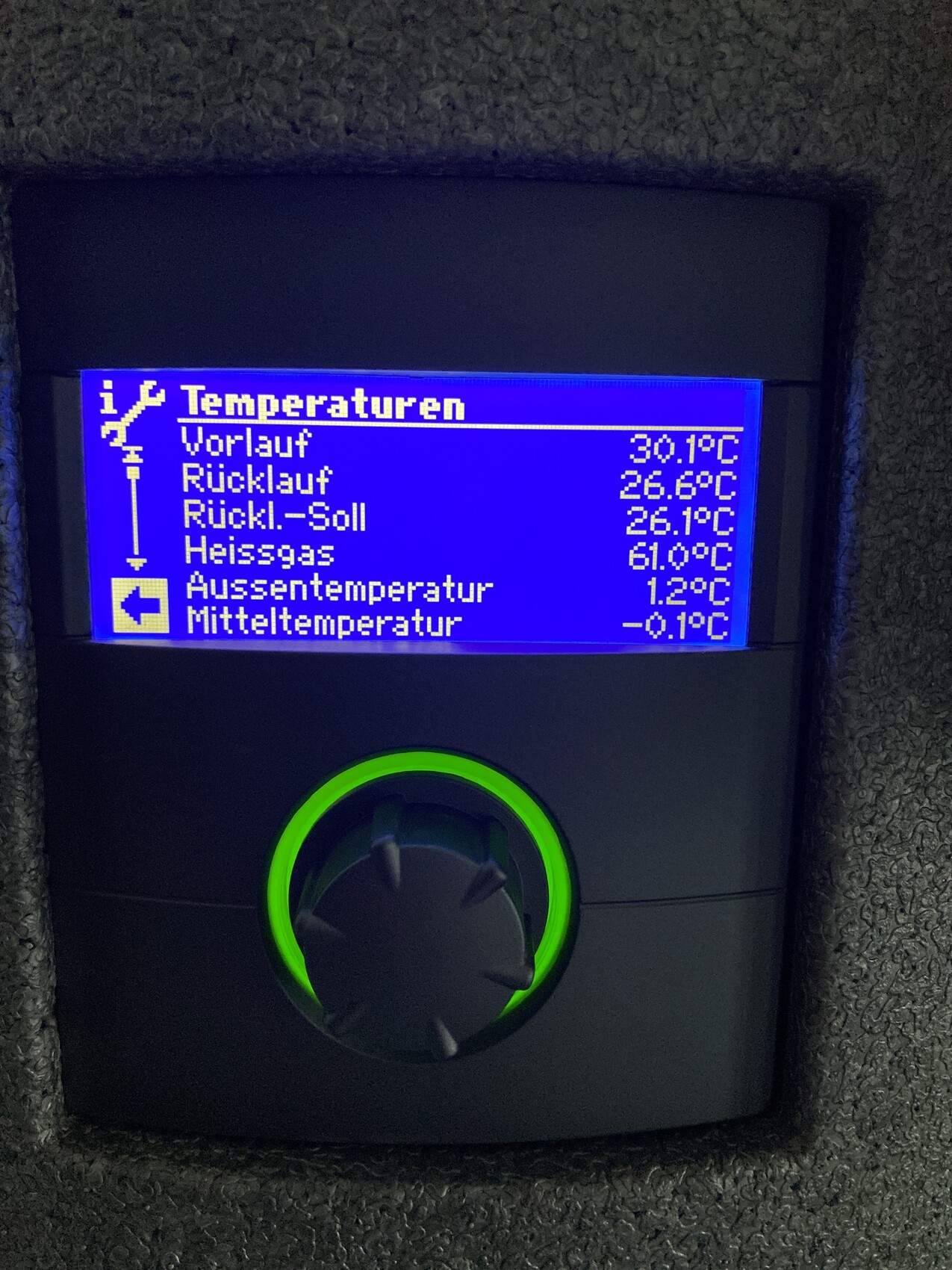 Thermostat mit blauem Display zeigt Vorlauf 30,1°C und Rücklauf 26,9°C; grün beleuchteter Drehknopf.