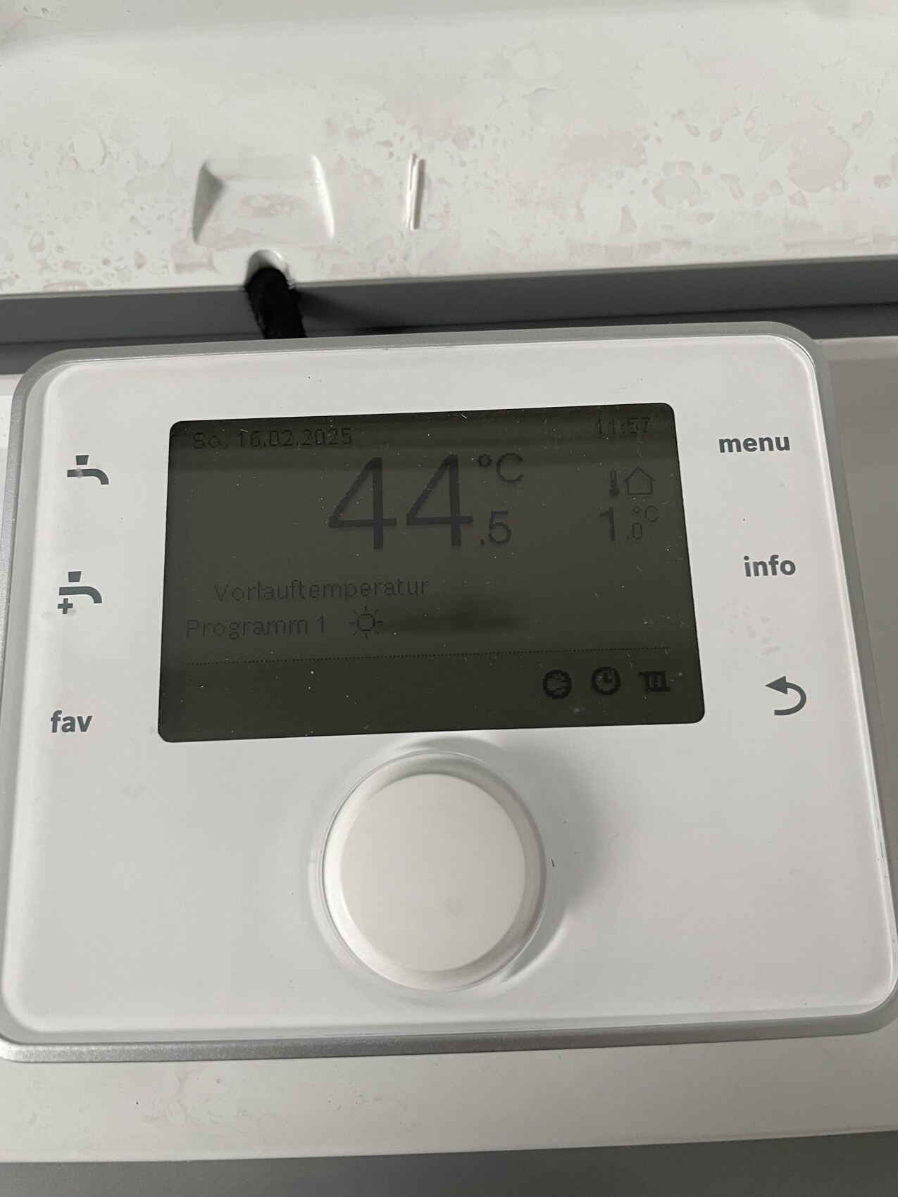 Weißer, wandmontierter Thermostat mit Display zeigt Vorlauftemperatur 44,5 °C.