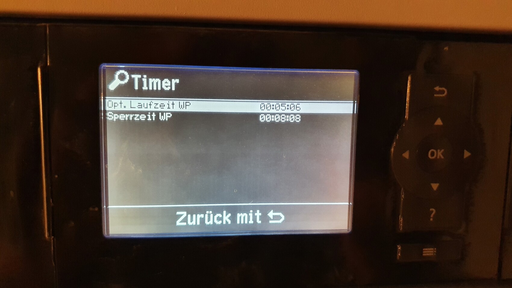 Kameradisplay zeigt Timer-Menü mit Opt. Laufzeit WP und Sperrzeit WP, Pfeil-/OK-Taste rechts.