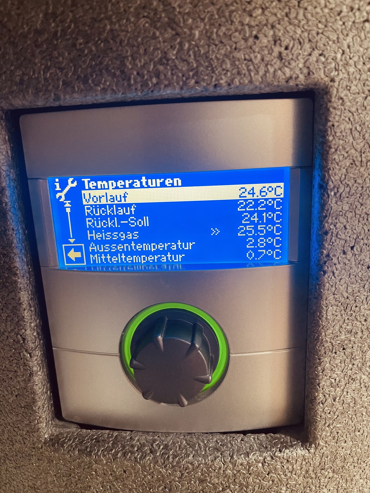 Heizungsregler: blaues Display mit Vorlauf-, Rücklauf- und Außentemperaturwerte, grüner Knopf.