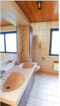 Doppelwaschbecken im Bad mit beige Keramikfliesen, Holzdecke und Fenster