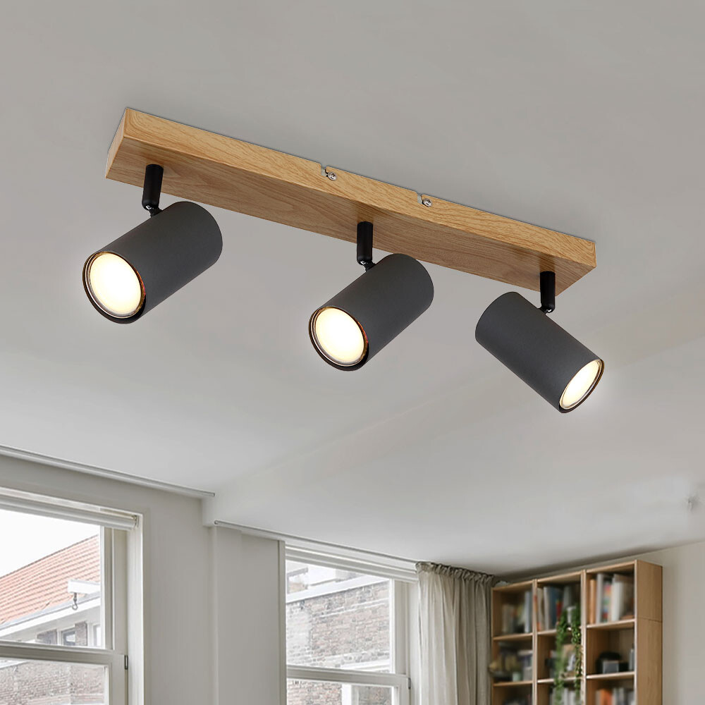 Dreiflammige Deckenleuchte mit Holzbalken und schwarzen Spots im Wohnzimmer.