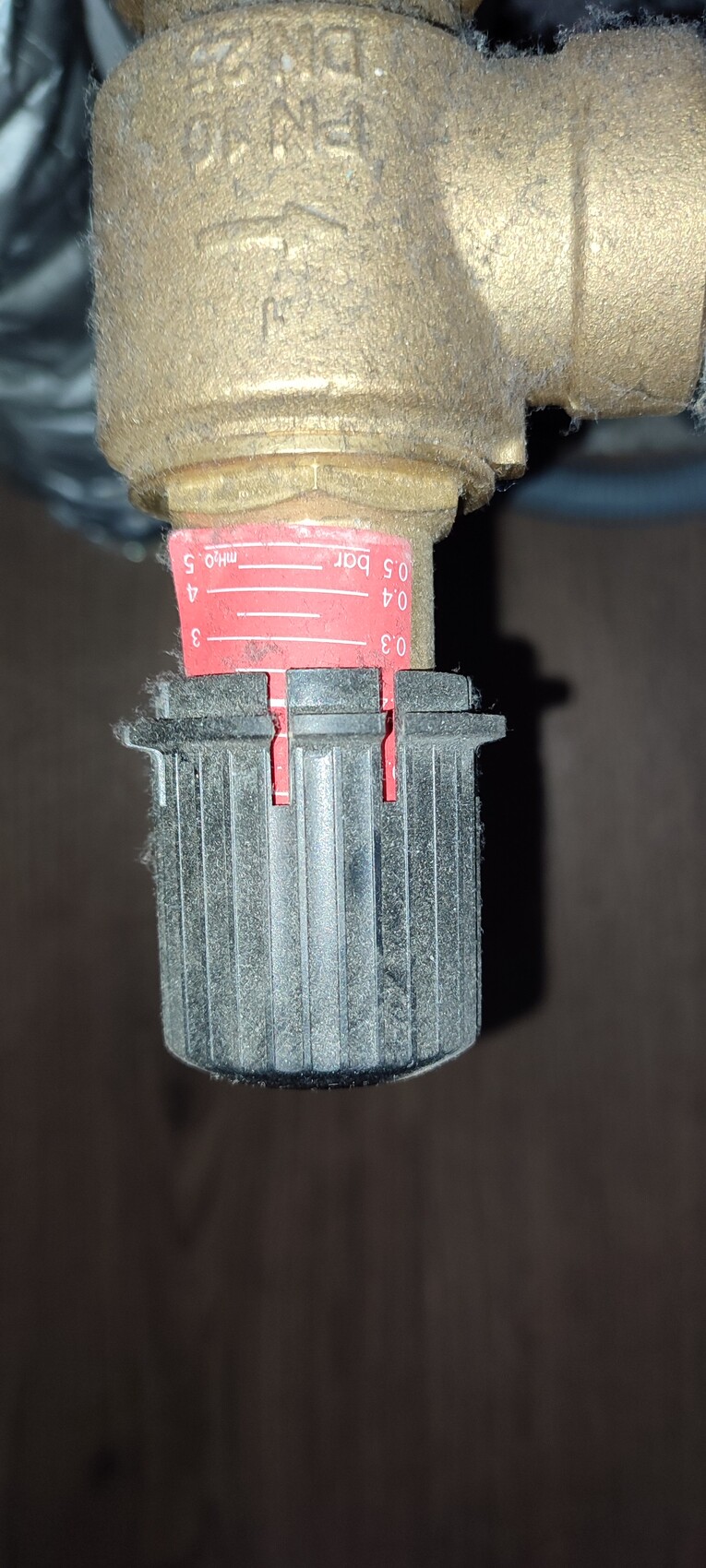 Nahaufnahme eines Messingventils mit roter Einstellskala (0–5 bar) und grauem Griff.