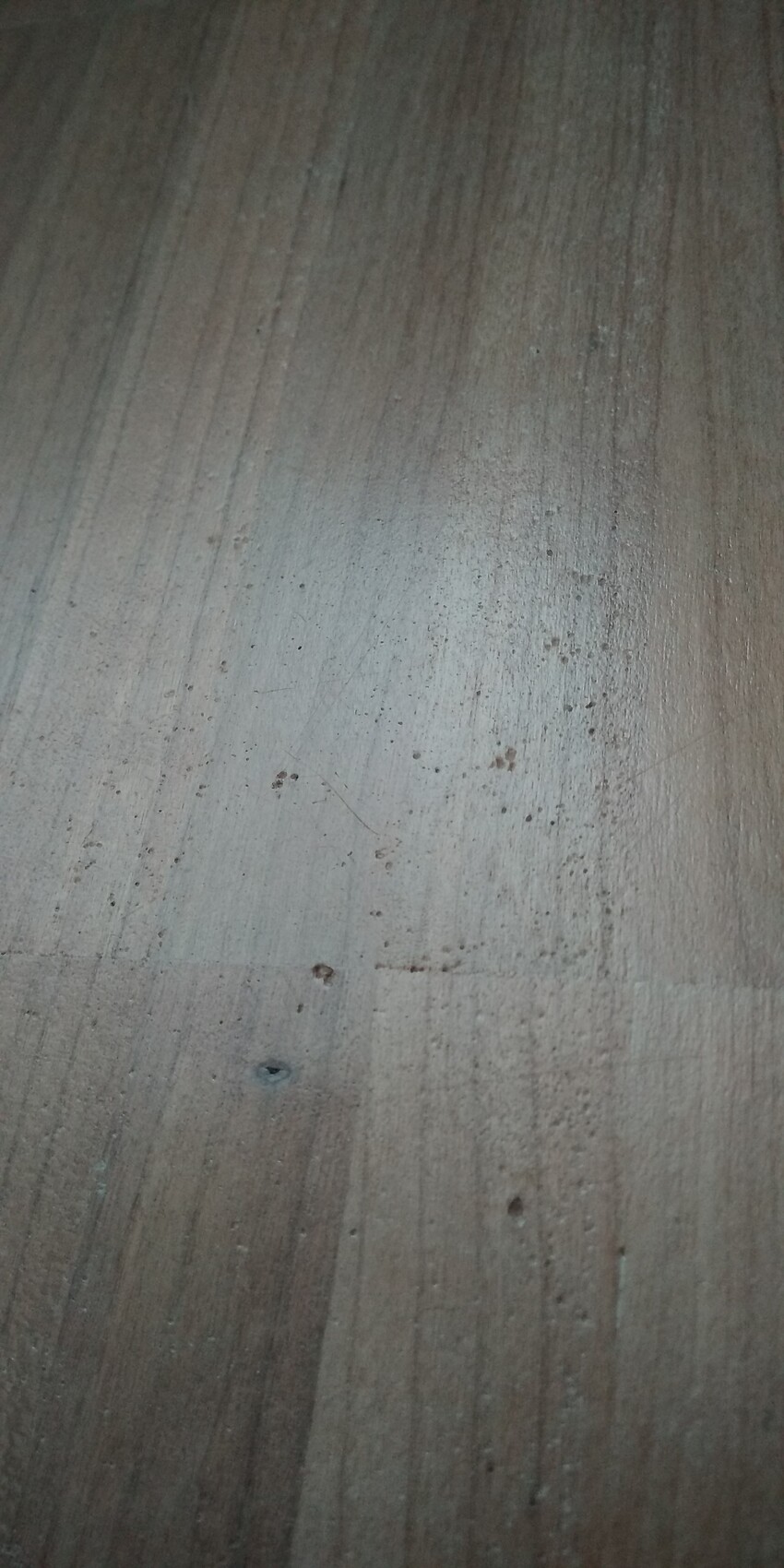 Nahaufnahme einer Holzoberfläche mit Maserung, Kratzern und Flecken.