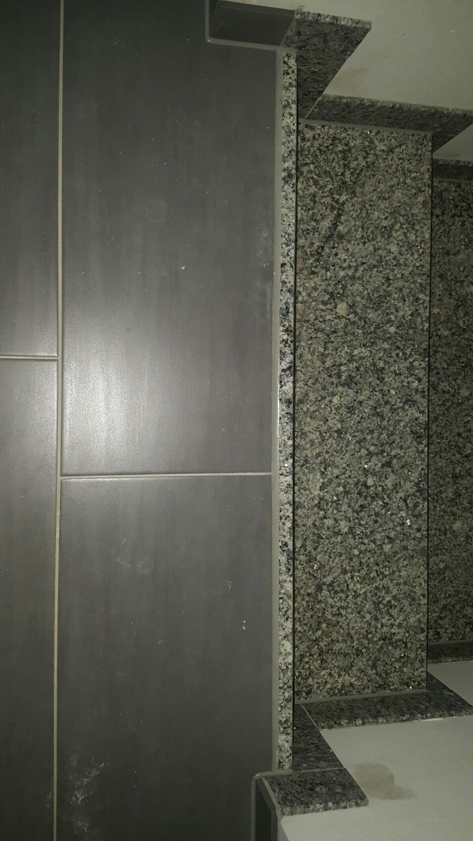 Dunkle Küchenfronten neben grauer Granit-Arbeitsplatte in einer Küche.