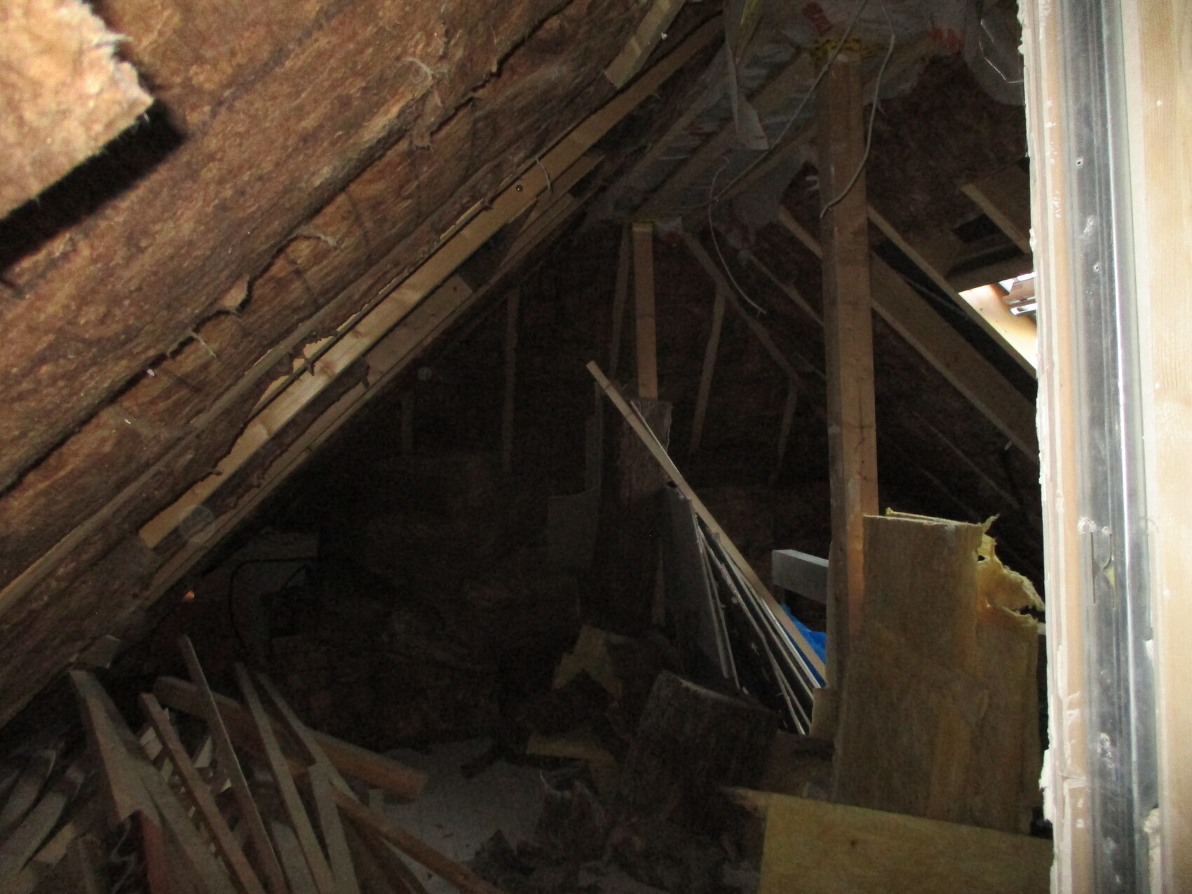 Dachboden mit Holzbalken und Gerümpel, dunkler Lagerraum.