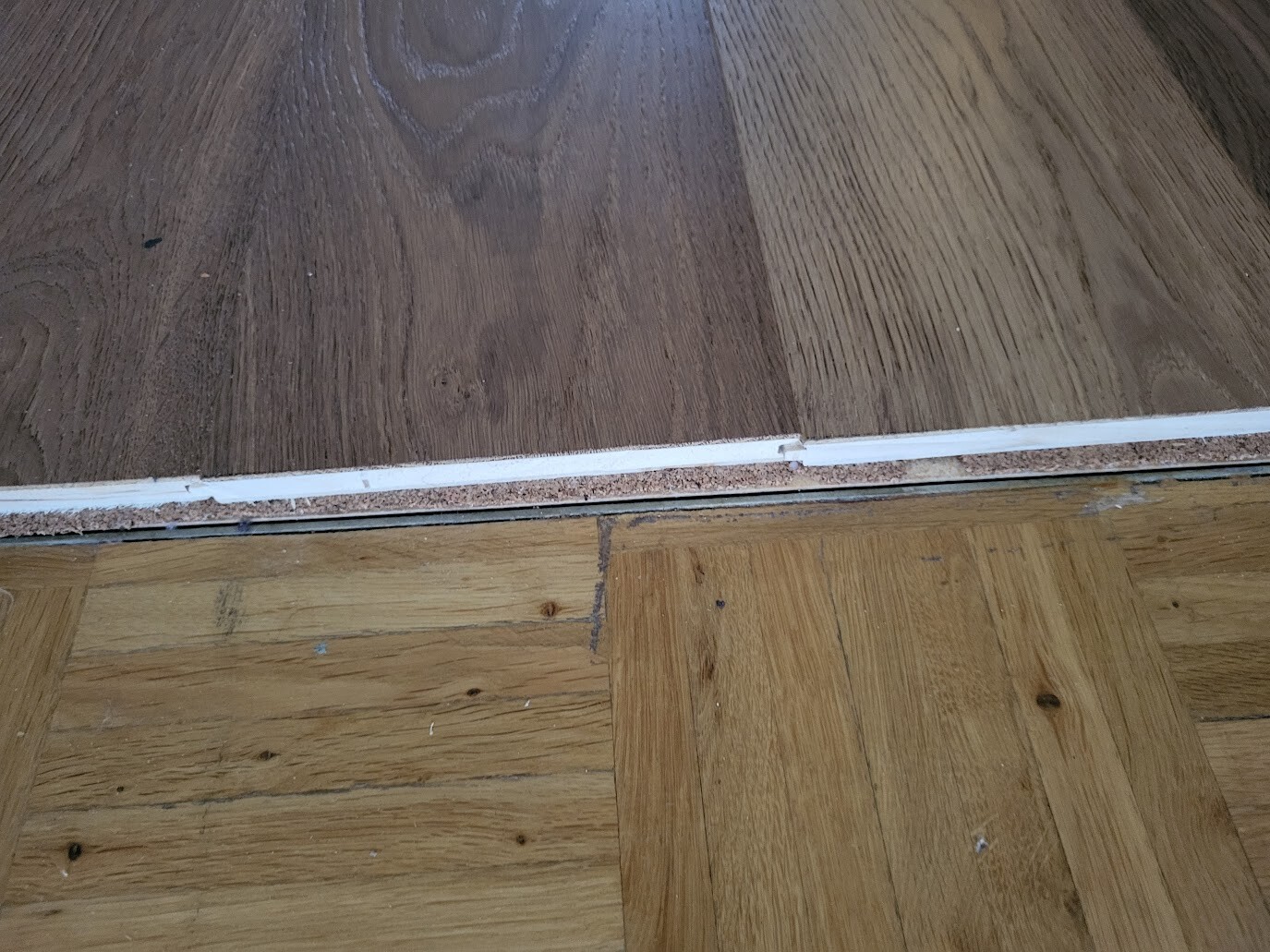 Übergang zwischen dunklem Oberboden und hellem Unterboden mit weißer Türschwelle.