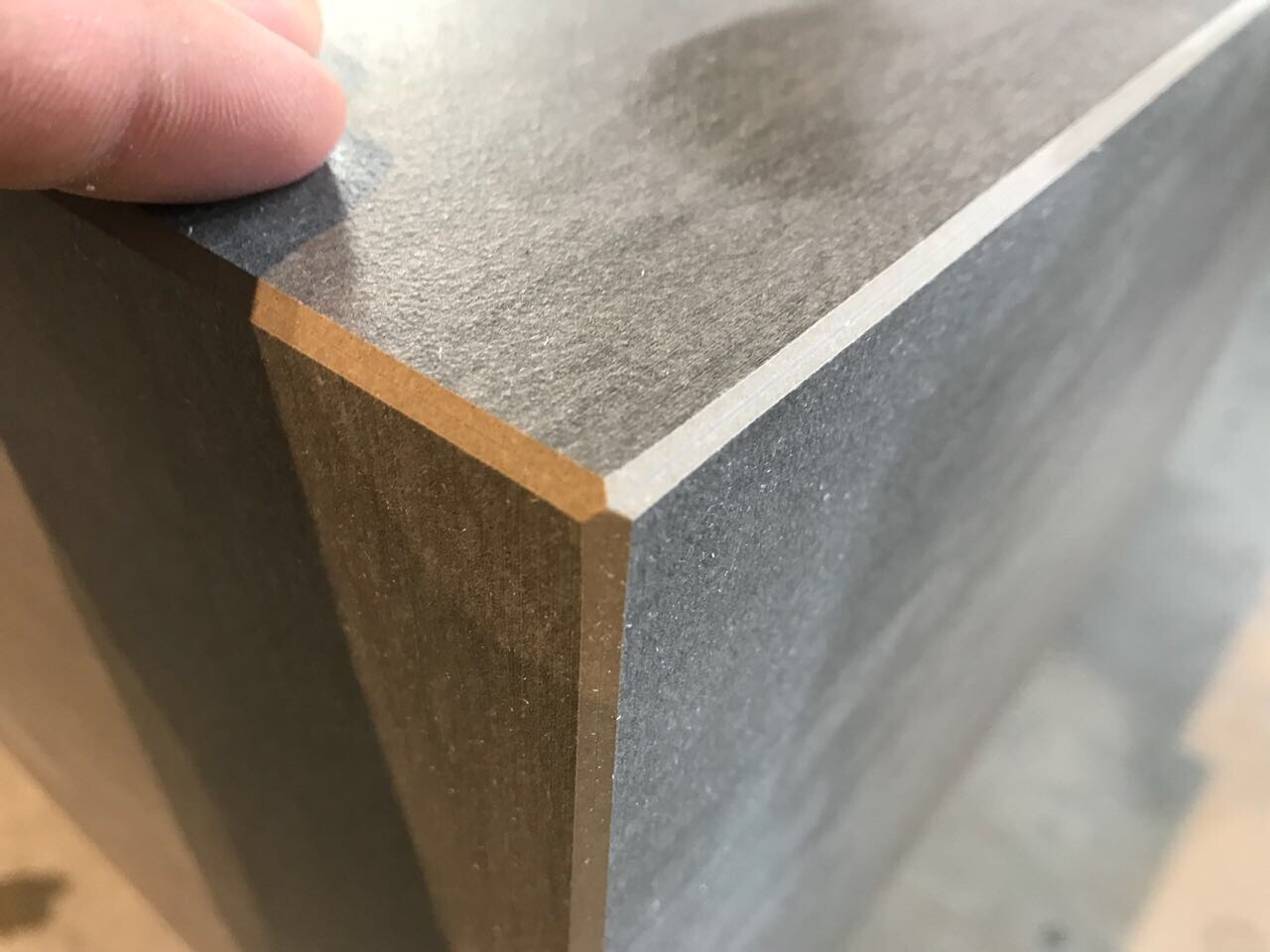 Nahaufnahme einer dunklen Laminatplatte mit heller Kante und Ecke