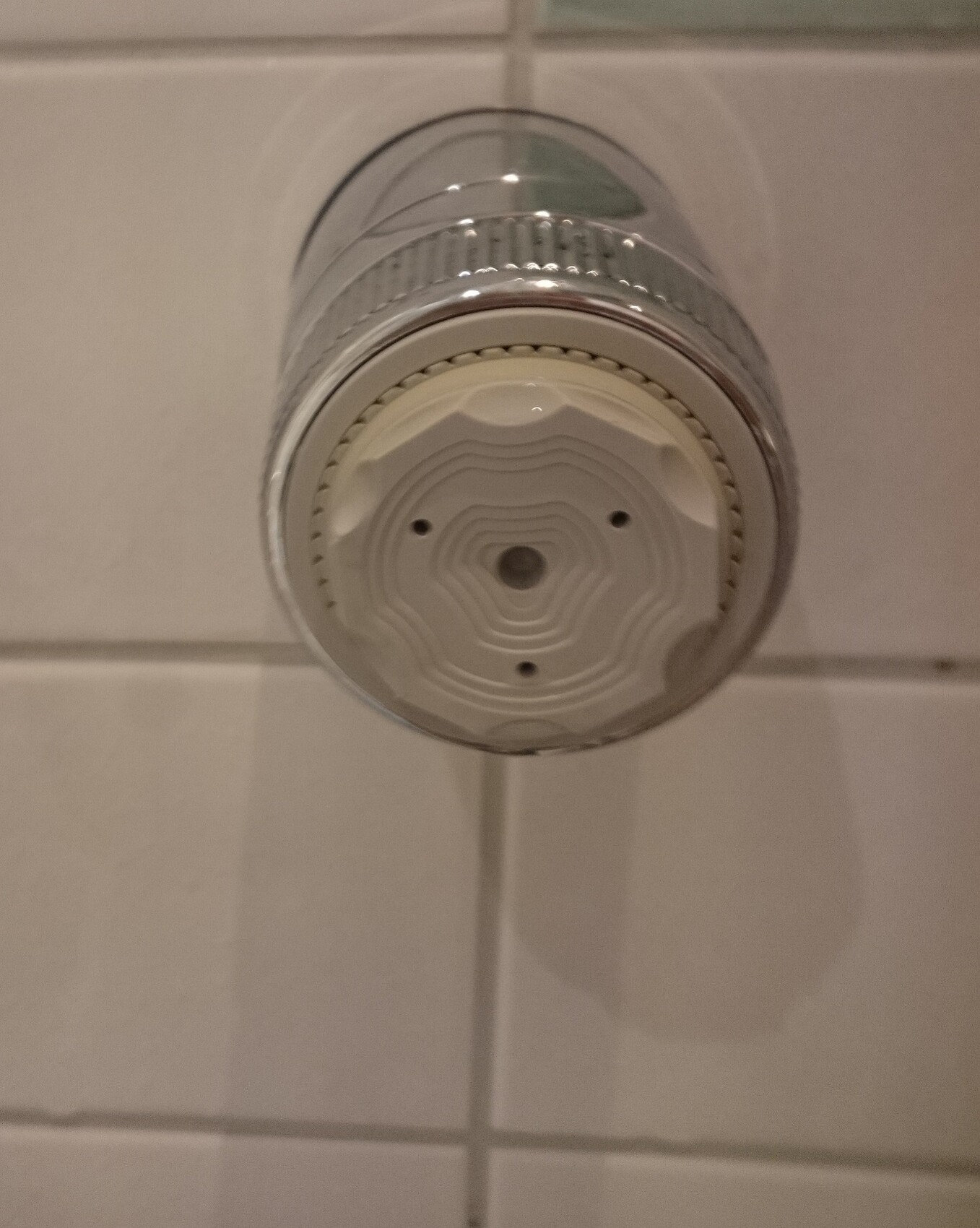 Nahaufnahme einer chromenen Duscharmatur mit Thermostat-Drehknopf vor weißen Fliesen
