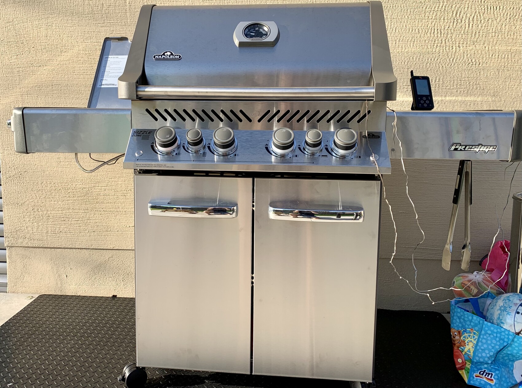 Großer Edelstahl-Gasgrill mit Thermometer am Deckel, sechs Knöpfe und Unterschränke.