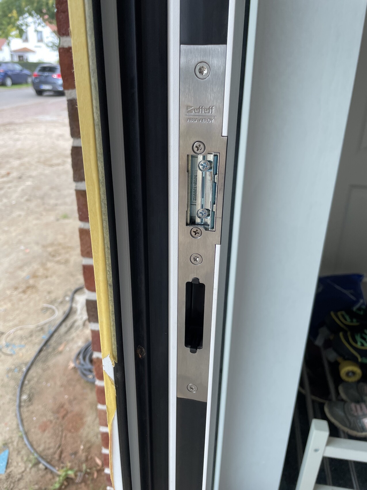 Nahaufnahme des Türschlosses am Türrahmen, Metallplatte mit Schrauben (ASSA ABLOY).