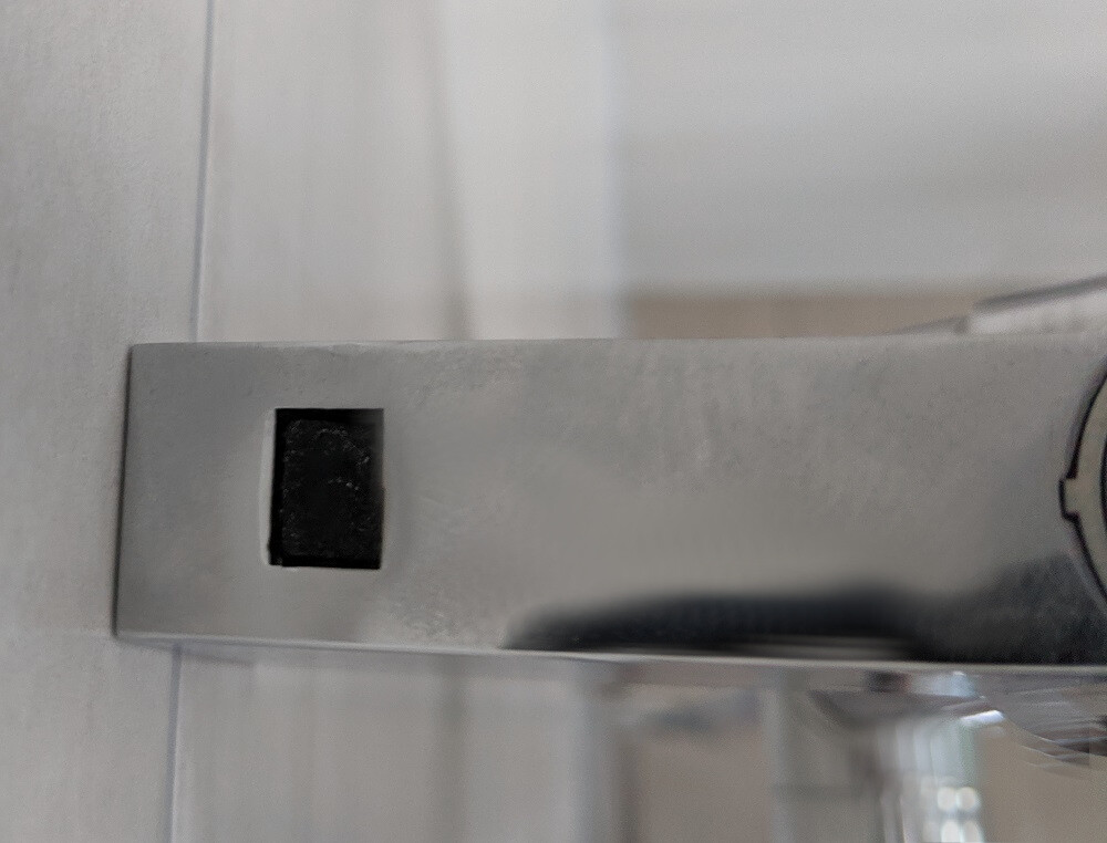 Nahaufnahme eines silbernen Metall-Türgriffs mit rechteckigem schwarzen Schlitz in der Grundplatte.